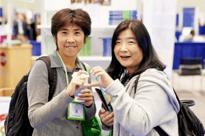 2 conference attendees making a heart with their hands