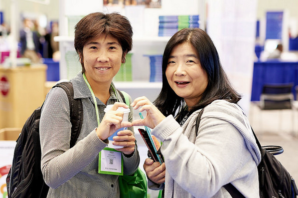 2 conference attendees making a heart with their hands