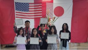 People holding certificates in front of US and Japan flags